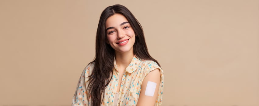 The smiling woman with a bandage on her arm celebrating good health and wellness. photo
