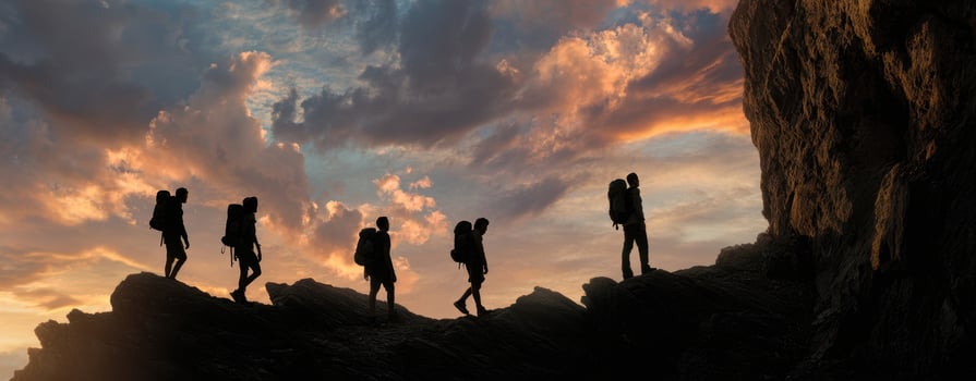 The silhouette of hikers ascending a rocky path against a stunning sunset backdrop. photo
