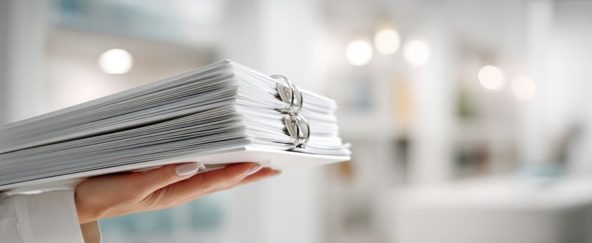 The hand holding a stack of organized documents in a modern office setting photo