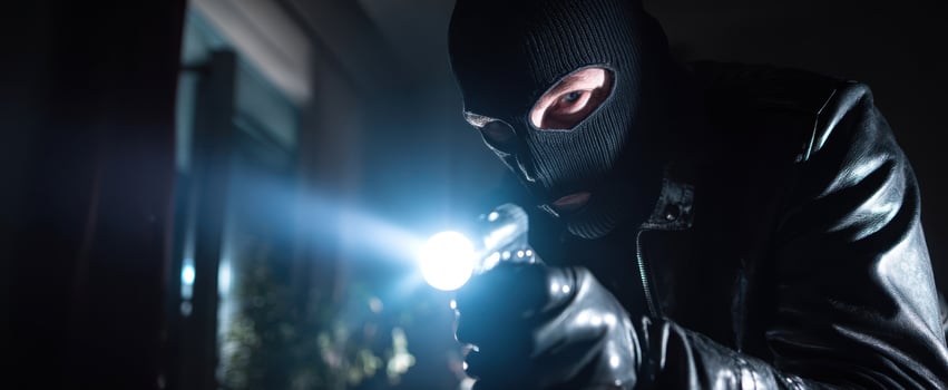 The masked intruder with a flashlight in a dimly lit room. photo