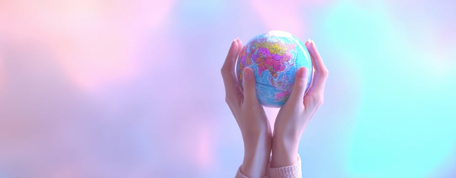 The hands holding a colorful globe against a dreamy pastel background photo