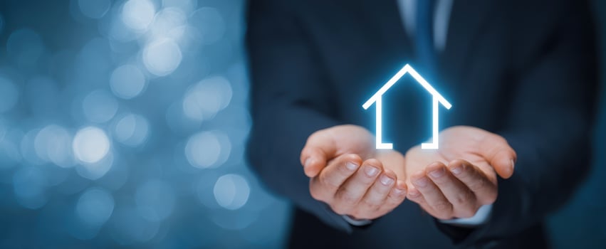 The glowing house icon held between hands representing homeownership and security. photo