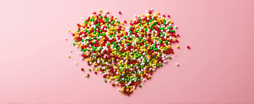 The colorful heart made of sweet sprinkles on a pastel background. photo