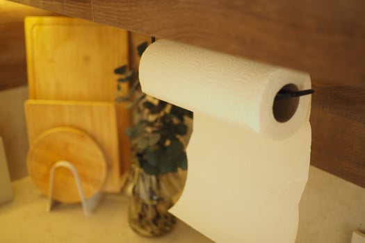 Kitchen paper towel roll hangs near wooden cutting boards photo