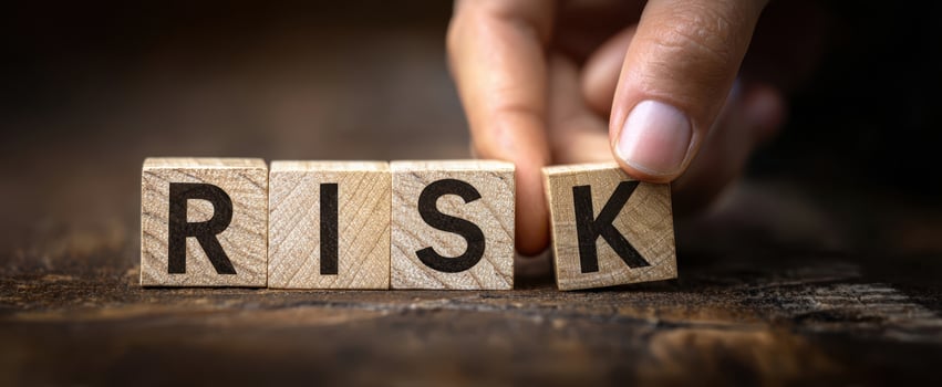 The hand arranging wooden blocks to spell the word 'RISK' on a table. photo
