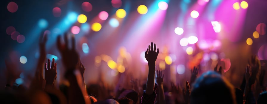 The hands of an excited crowd reaching towards vibrant concert lights photo