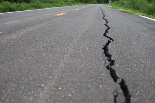 The road surface is cracked, the asphalt is damaged, cracked. photo