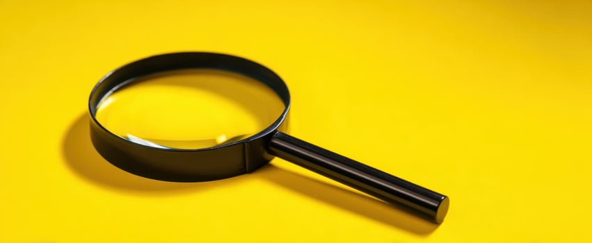 The magnifying glass resting on a vibrant yellow background for symbolic exploration. photo