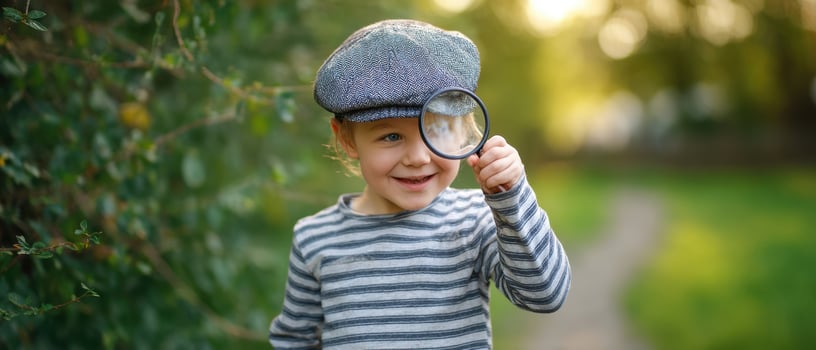 The cheerful child with a magnifying glass exploring the lush greenery outdoors. photo