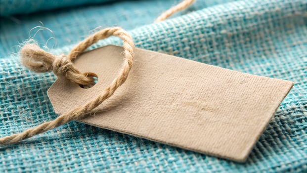Blank Brown Paper Tag with Twine on Textured Blue Fabric Close Up photo