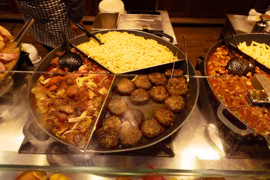 Delicious assortment of cooked dishes including pasta, meat patties, and savory sides in a buffet setting photo