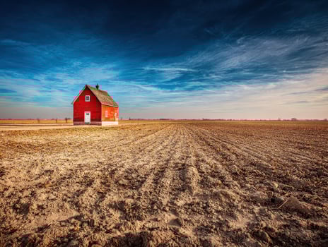 A red house in a field with a blue sky photo