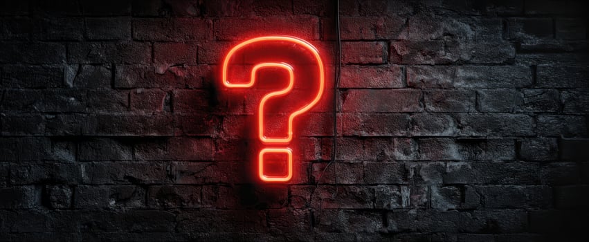 The glowing neon question mark illuminating a dark brick wall. photo