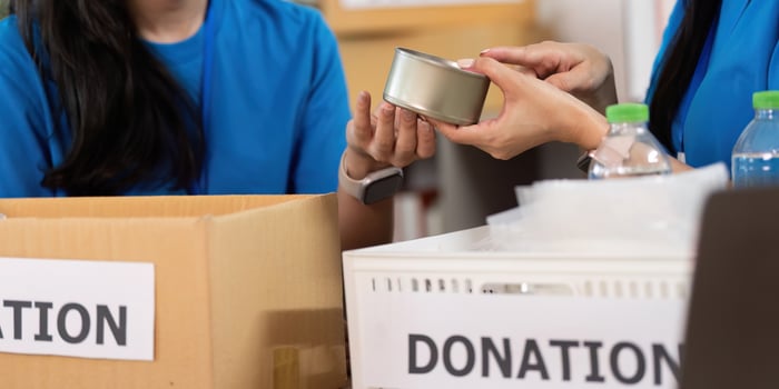 Volunteer collaboration. Close-up of women exchanging donation items with care. photo