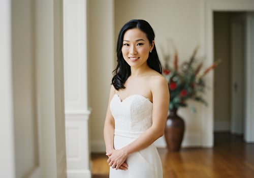 Bride in wedding dress smiling in foyer with flowers behind her, portrait photo