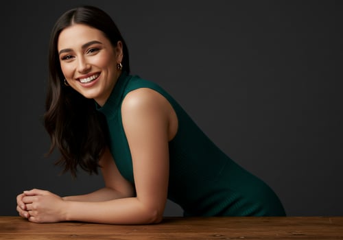 Cheerful woman in green dress leans on table, for beauty or fashion campaign photo