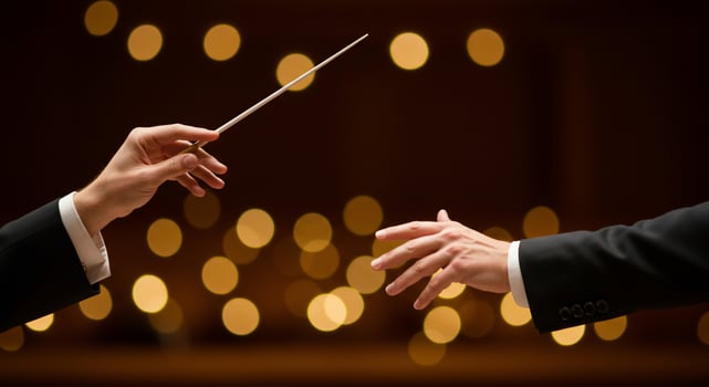 Conductor's Hands with Baton Leading Orchestra Against Bokeh Lights photo