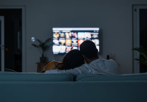Couple watching television together on couch at home in the evening for leisure photo