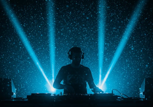 DJ playing music in night club with concert lighting and snowfall effect photo