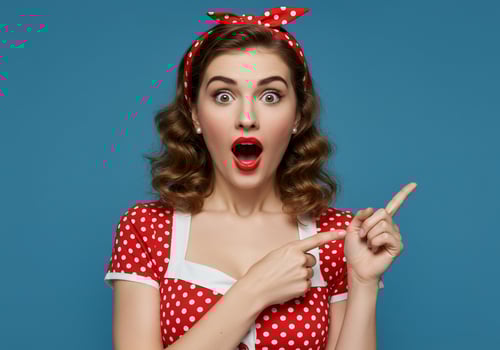 Excited woman in red dress points to right with blue backdrop, for advertising photo