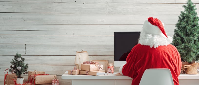 The Santa Claus Working at a Computer Surrounded by Festive Decorations photo