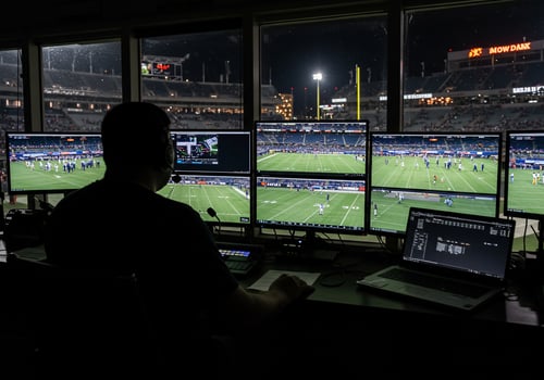 Football director overseeing live stadium game broadcast at night using computers photo