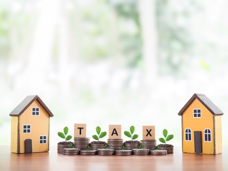 Miniature house, Wooden blocks with the word TAX and plants growing up on stack of coins. The concept about saving money to payment tax for house, Property investment, House mortgage, Real estate photo