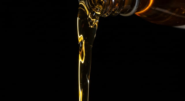 A bottle of oil being poured into a glass photo