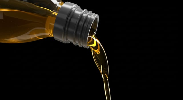 A bottle of oil pouring into a black background photo