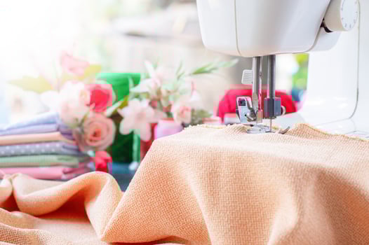 Sewing machine working with brown fabric, sewing accessories on the table, stitch new clothing. photo