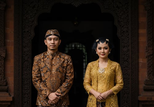 Javanese couple in traditional attire standing in front of carved wood door photo
