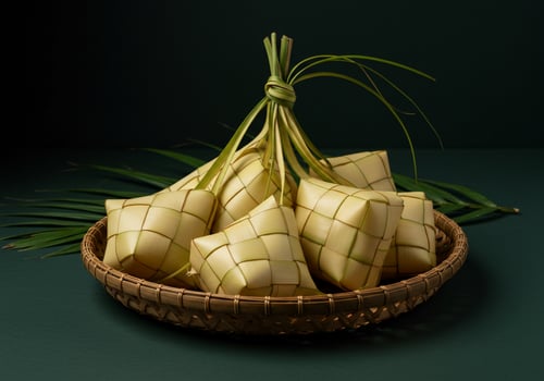 Ketupat in woven basket, for traditional celebration. Green background. Food photo