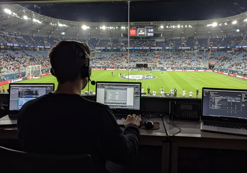 Man broadcasting live soccer game at stadium with crowd, for social media photo