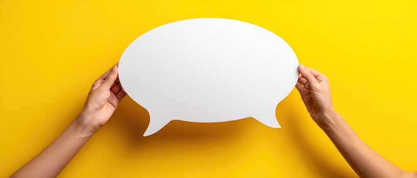 The blank speech bubble held by hands on a bright yellow background photo