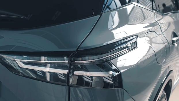 Sleek modern car rear view showcasing stylish taillights and reflective surfaces in a contemporary showroom environment with vibrant lighting photo
