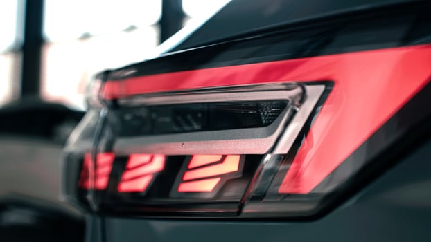 Close-up view of modern car taillight showcasing sleek design and vibrant colors in a stylish showroom environment emphasizing automotive elegance photo