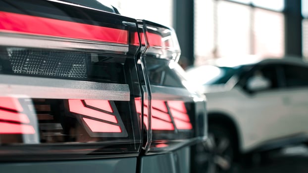 Close-up view of modern car taillight showcasing sleek design and vibrant red illumination in a stylish showroom environment photo