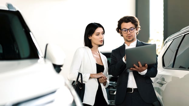 Couple discussing car options with a salesperson in a modern showroom, showcasing various vehicles and a digital tablet for information photo