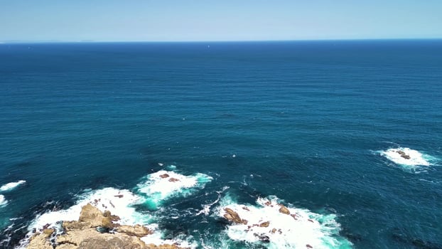 Captivating Aerial Views of Turquoise Ocean Waves Fiercely Crashing on Rocky Shores photo