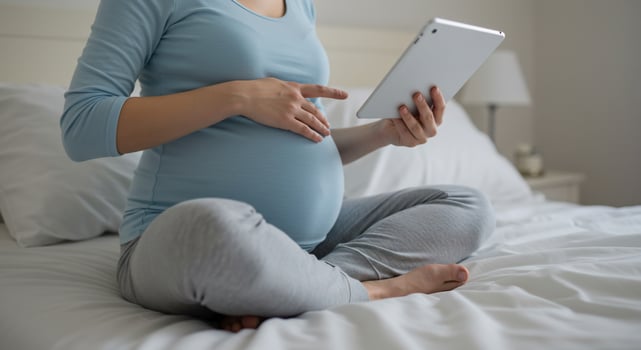 Pregnant Woman Using Digital Tablet on Bed photo