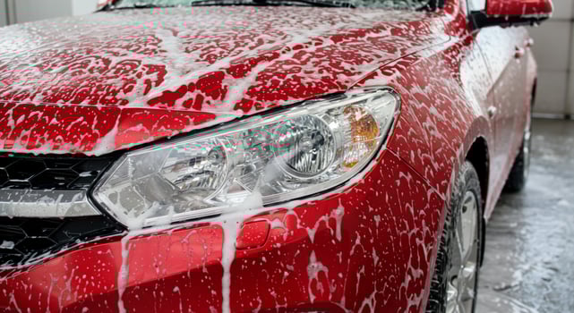 Red car getting washed with soap for a perfect clean, in a washing facility photo