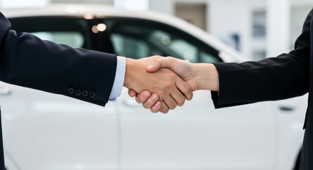 Two business people shaking hands in front of a car photo