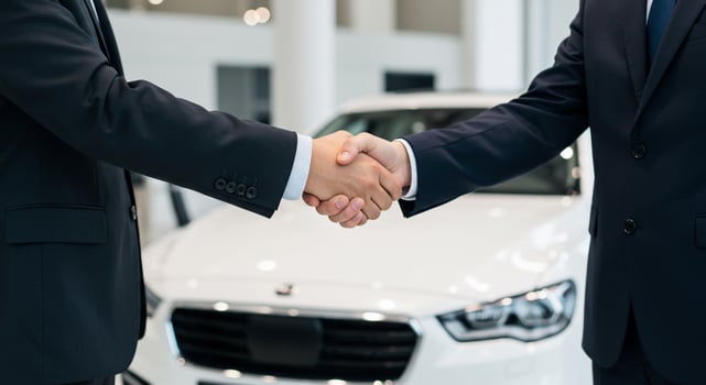 Two men shaking hands in front of a car photo