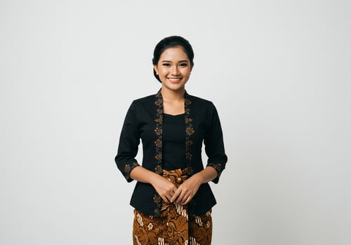 Smiling Asian lady poses in Kebaya outfit with batik cloth against plain background photo