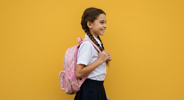 A girl in a school uniform is standing against a yellow wall photo