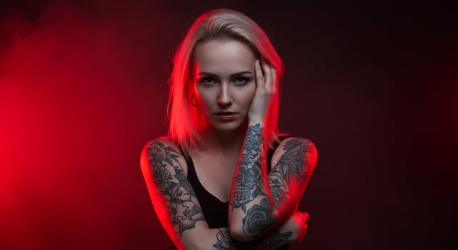 Tattooed blond woman poses. Red light, smoke, mysterious mood. Modeling use photo