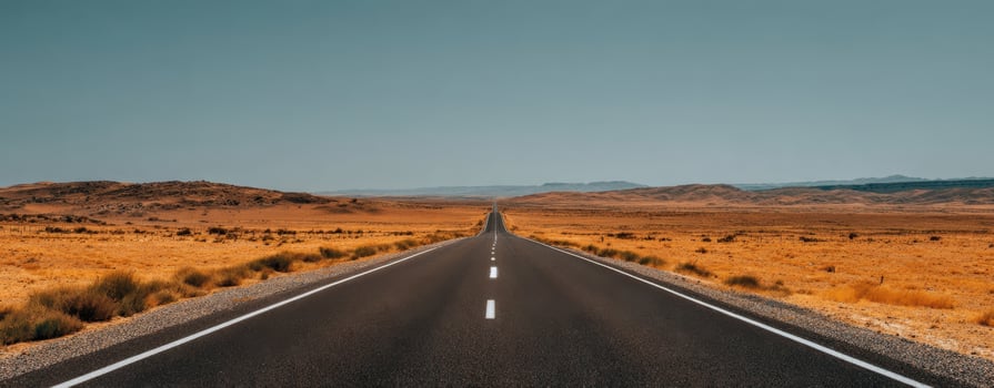 The open road stretching through a vast golden desert landscape. photo