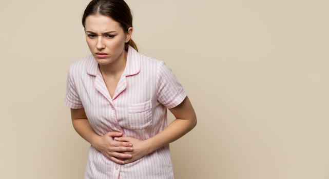 Woman in Pajamas Experiencing Abdominal Pain on Beige Background photo