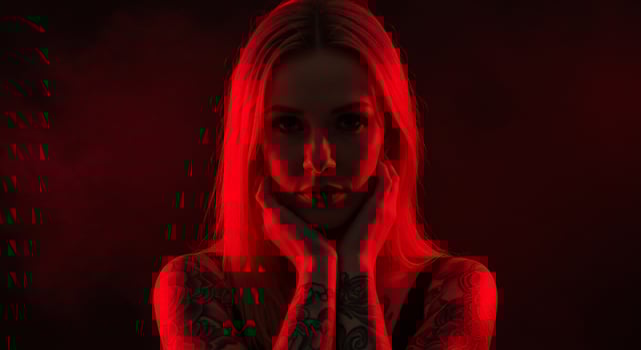 Woman with tattoos and blonde hair, lit by red light, posing for a fashion shot photo