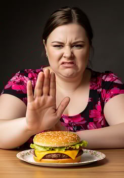 A woman sitting at a table with a hamburger and a plate of food photo